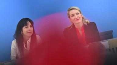 Zwei Frauen lächeln in die Kameras