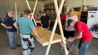 Männer arbeiten gemeinsam an einem Holzstand.