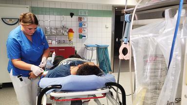 Eine Frau kümmert sich um einen Mann, der auf einer Liege liegt.