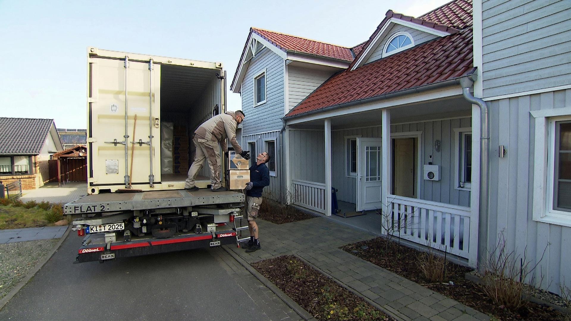 Umzugsmitarbeiter Mario Weichler übergibt einen Karton mit Umzugsgut an einen Kollegen.