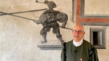 Älterer Herr in Tracht vor Wandgemälde 