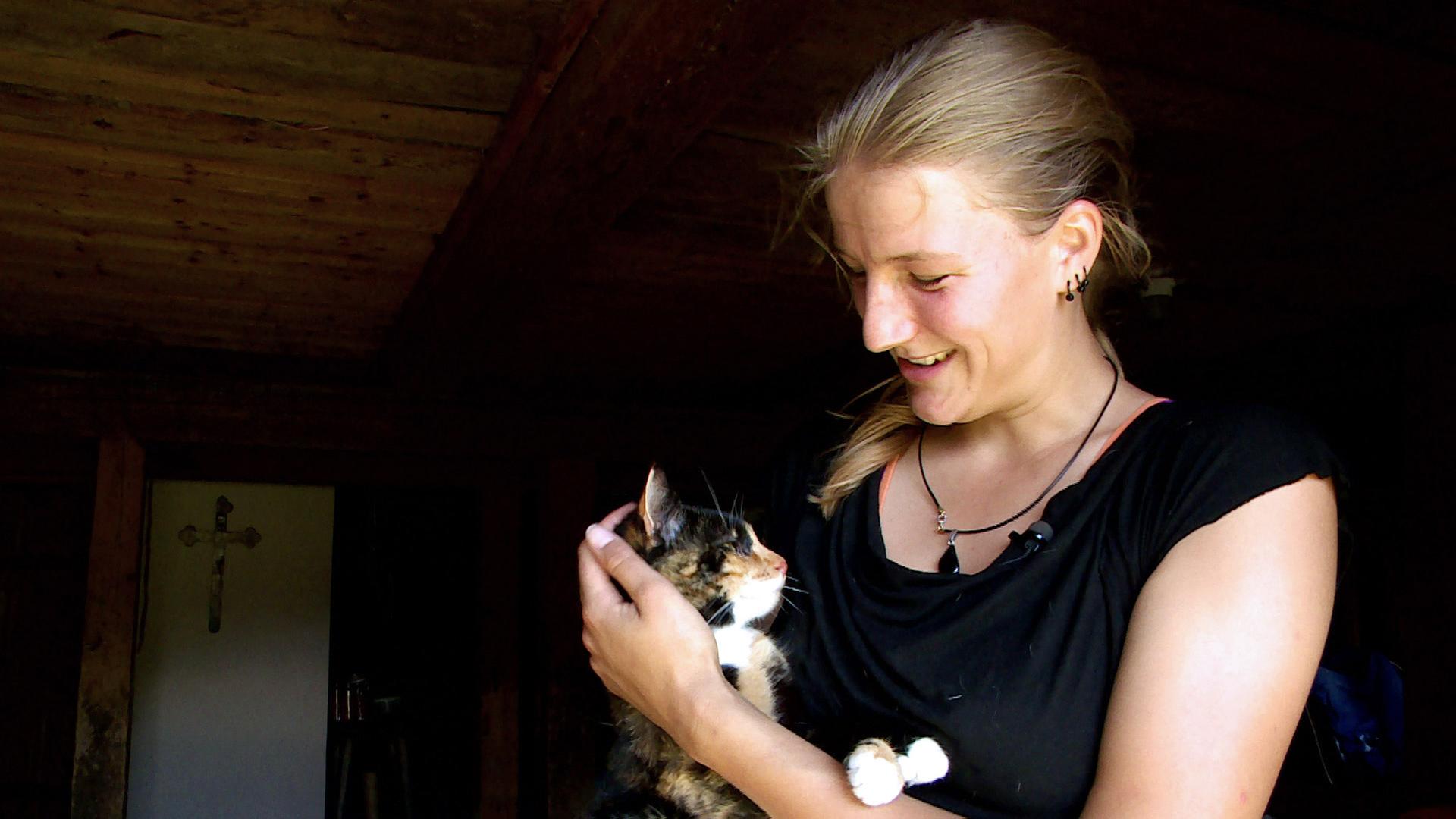 Eine junge Frau mit einer Katze auf dem Arm.