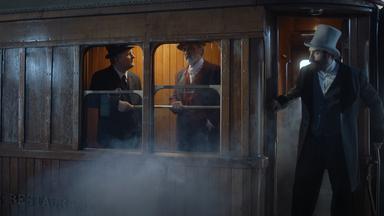 "Die glorreichen 10 – Die krassesten Spurts der Geschichte": Spielszene: Blick von außen auf einen Waggon des Orient-Express. Innen sind zwei Männer im Anzug an den geöffneten Fenstern zu sehen. Daneben steht Georges Nagelmackers in der geöffneten Waggontür.