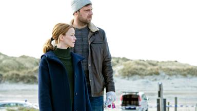 Eine Frau und eine Mann auf Dünen am Meer.