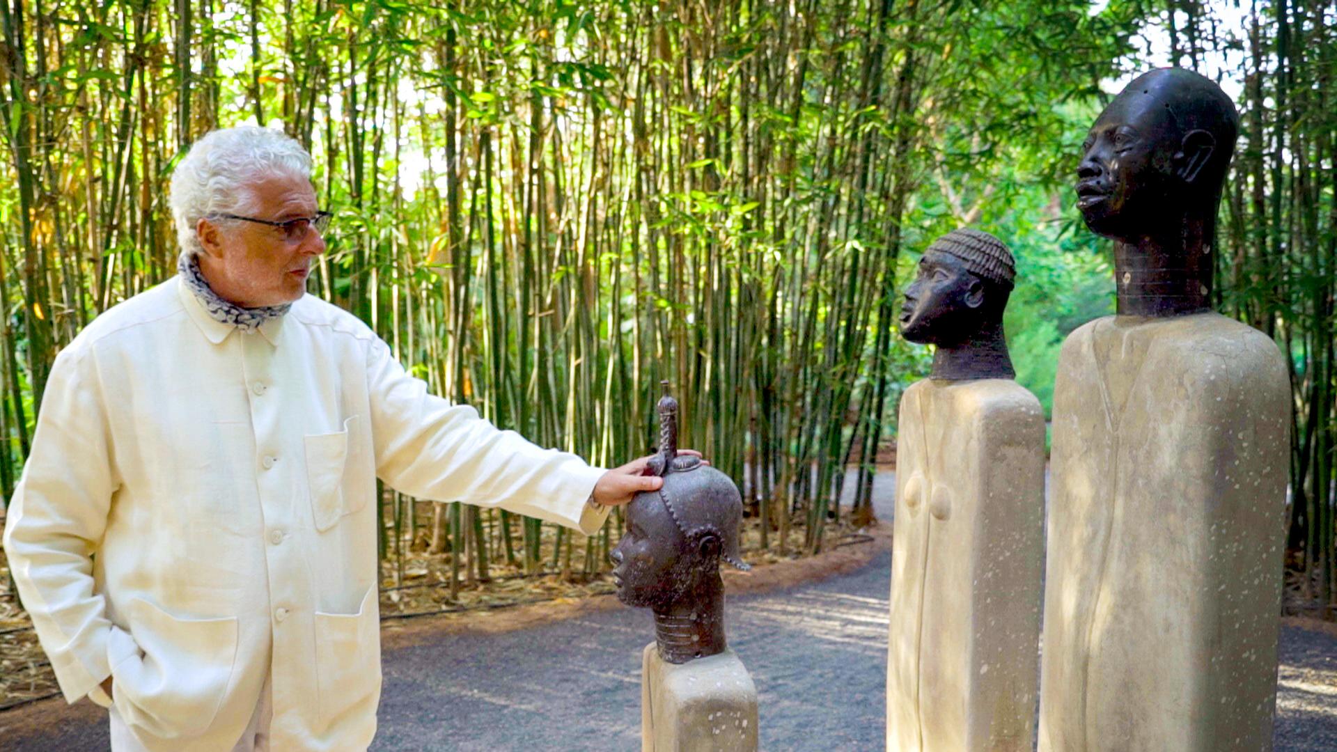 Mann legt eine Hand auf eine Skulptur.