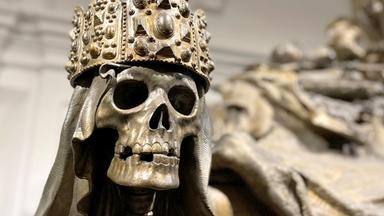 Aus Bronze gegossener Totenkopf mit Reichskrone auf einem Sarkophag