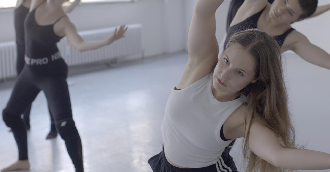 Frau mit langen Haaren und nach oben gestreckten Armen neigt sich zur Seite.