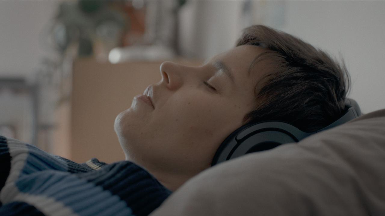 Nahaufnahme einer liegenden Frau mit Kopfhörern.