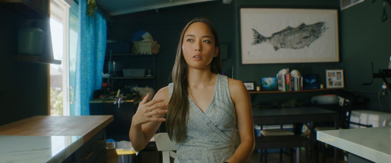 Sitzende Frau blickt frontal in die Kamera.