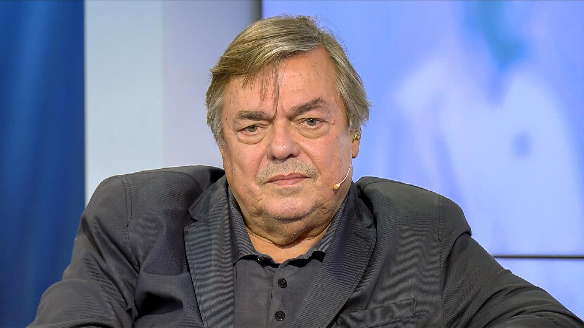 Älterer Mann mit graumeliertem Haar und dunklem Anzug.