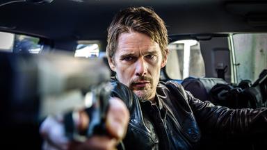 Travis Conrad (Ethan Hawke) sitzt in einem Auto und zielt mit einer Pistole aus dem Seitenfenster.