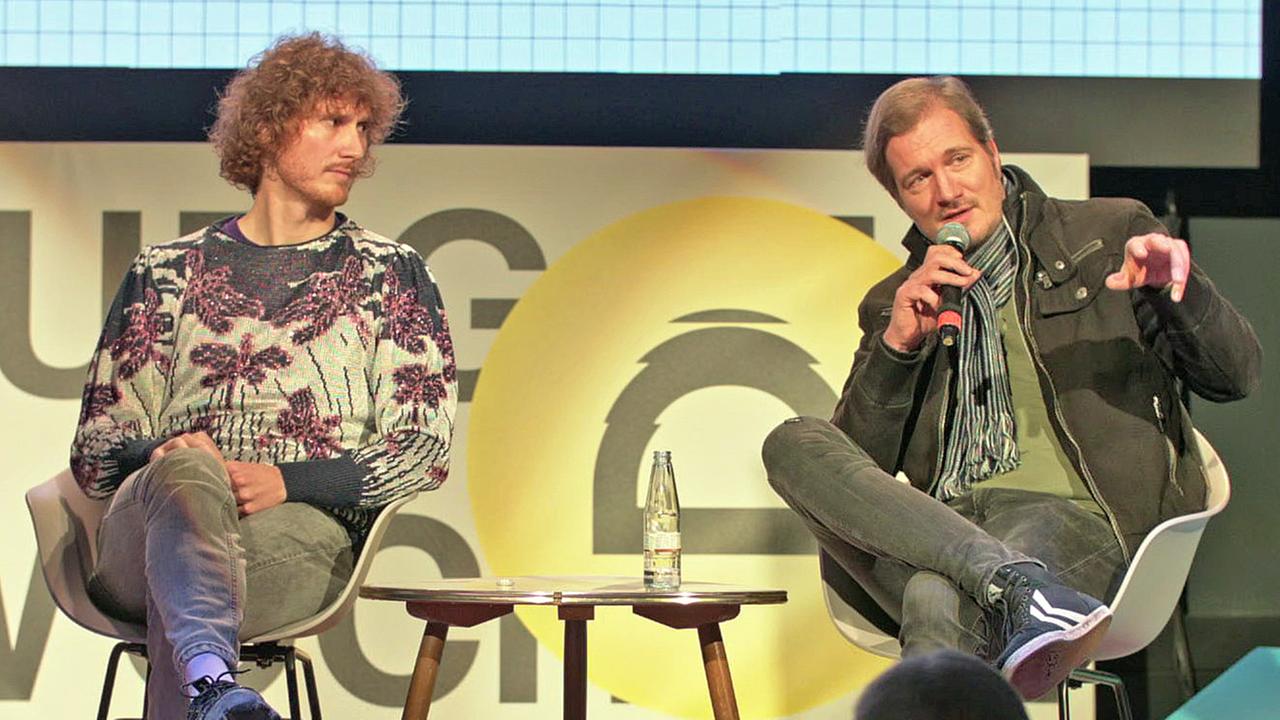 Lukas Marxt und Daniel Kötter sitzen auf einem Podium.