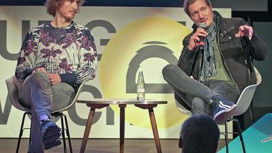 Lukas Marxt und Daniel Kötter sitzen auf einem Podium.