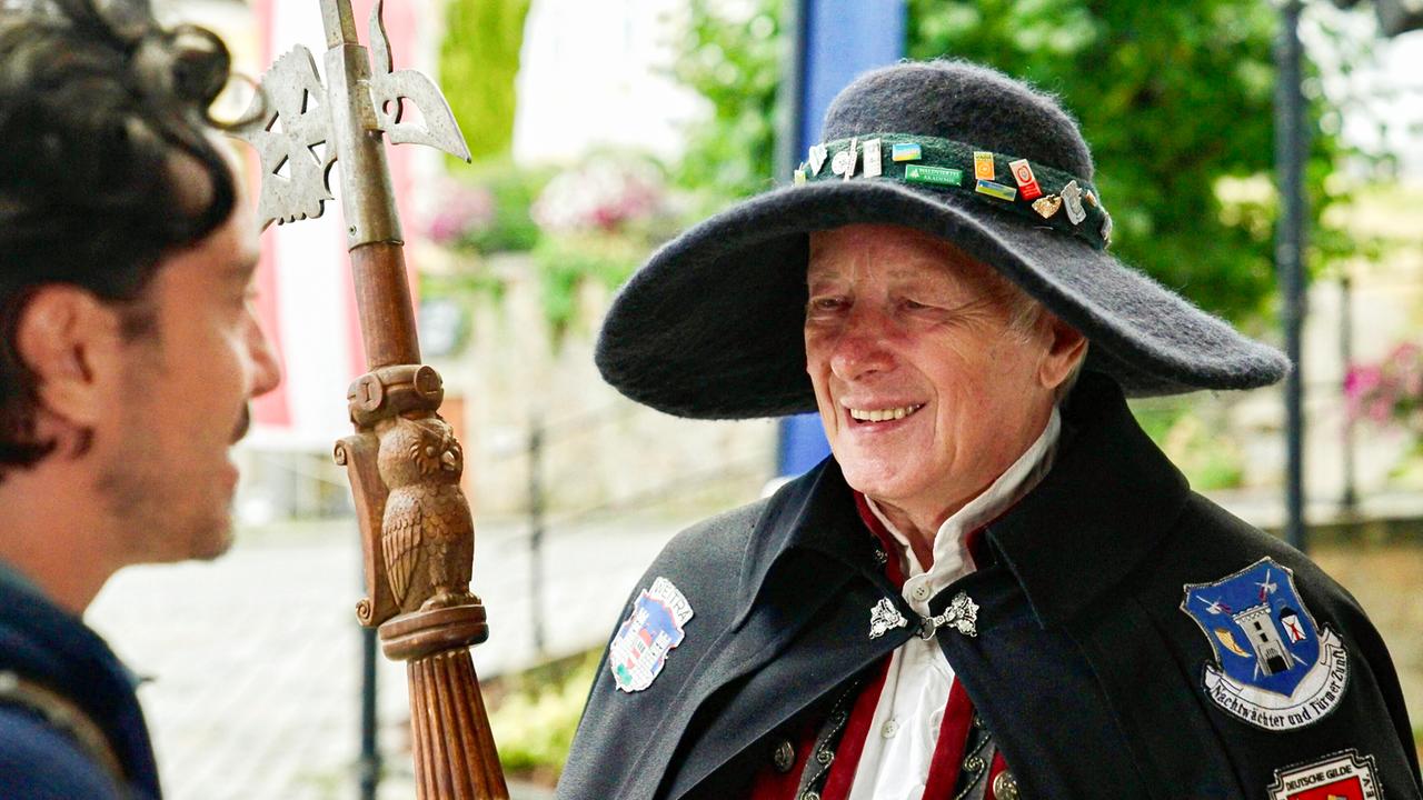 Mann in historischer Kleidung, mit einem anderen Mann im Gespräch