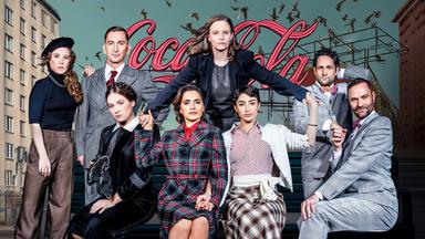 Auf dem Gruppenfoso sitzen drei Frauen und ein Mann in Business-Kleidung auf einem Sofa, hinter ihnen stehen nochmals zwei Frauen und Zwei Männer.