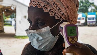 Ein Grenzgesundheitsbeamter am Grenzübergang Busunga zwischen Uganda und der Demokratischen Republik Kongo misst am 18. Mai 2026 in Bundibugyo die Temperatur eines Reisenden mithilfe eines kontaktlosen Infrarotthermometers.