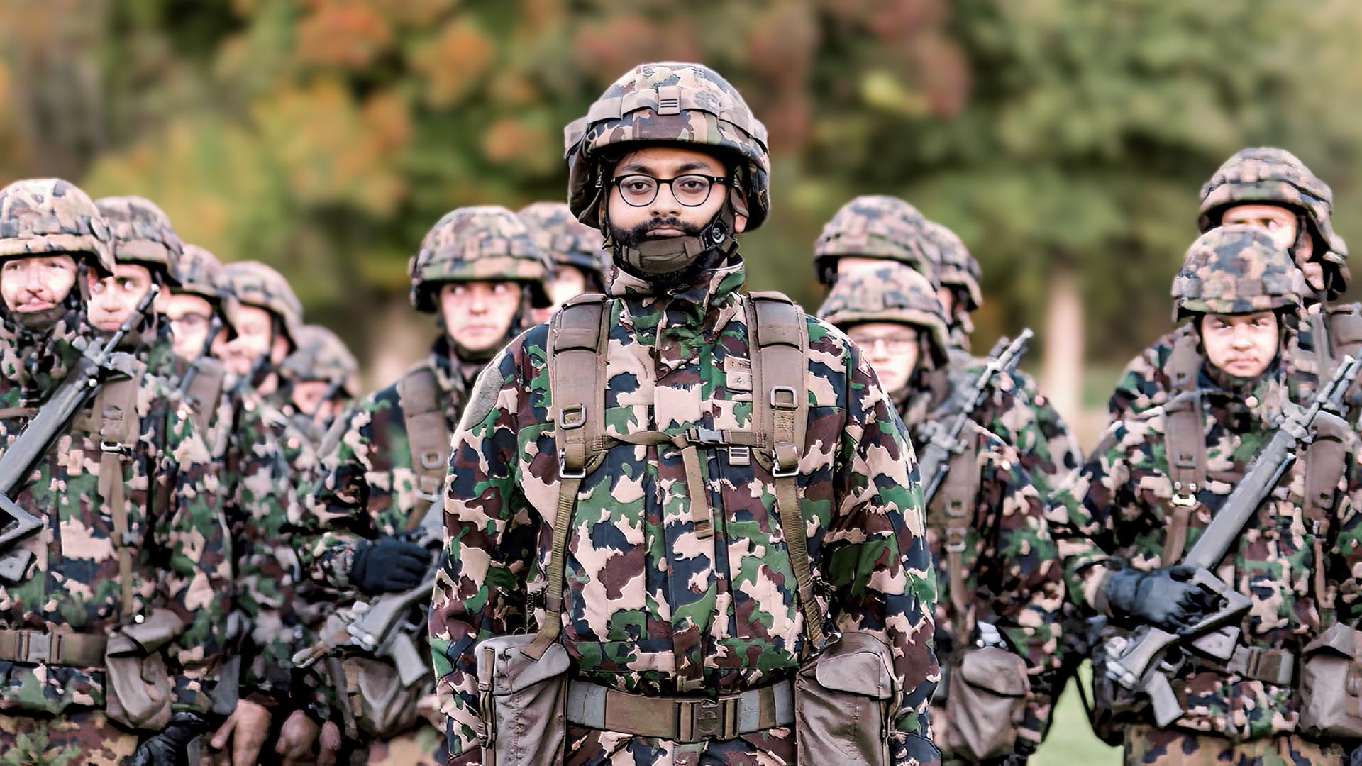 Eine Gruppe von Soldaten in Tarnuniform steht in Formation im Freien, im Vordergrund ein Soldat mit Brille und Bart.