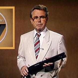 Eduard Zimmermann steht vor einem braunen Hintergrund mit dem Sendungslogo "Aktenzeichen XY ... ungelöst". Bekleidet ist er mit einem leicht glänzenden beigen Sakko, einem weißen Hemd und einer gestreiften Krawatte. In den Händen hält er ein Gewehr.