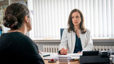 Eine Ärztin sitzt an einem Tisch. Ihr gegenüber sitzt eine Patientin.