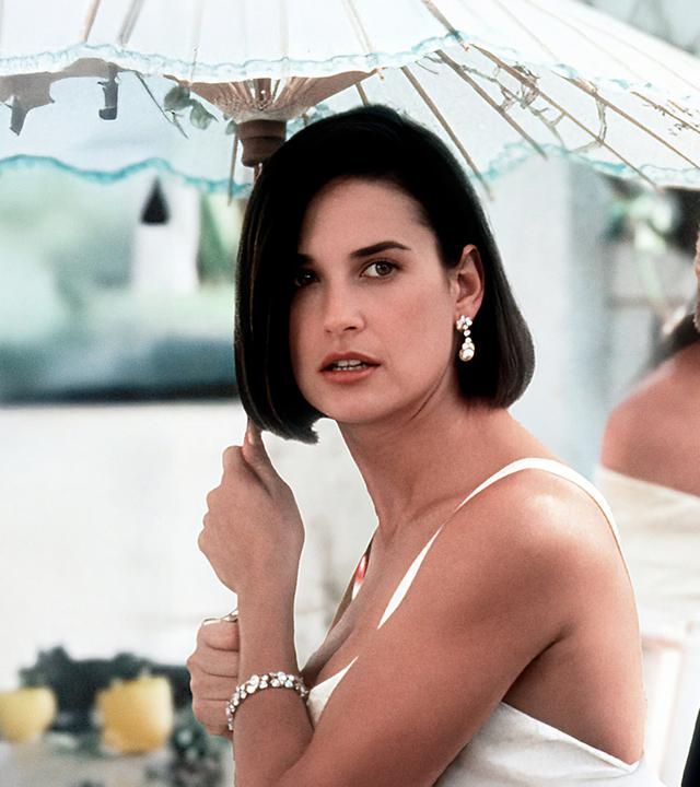 Eine dunkelhaarige Frau (Demi Moore) mit einem Sonnenschirm in der Hand mit einem blonden Mann (Robert Redford) an ihrer Seite
