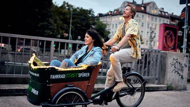 Ein Mann fährt eine Frau in einem Lastenrad.