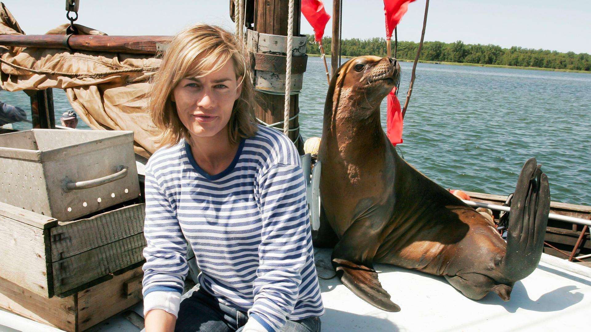 Eine Robbe und eine Frau an Deck eines Boots.