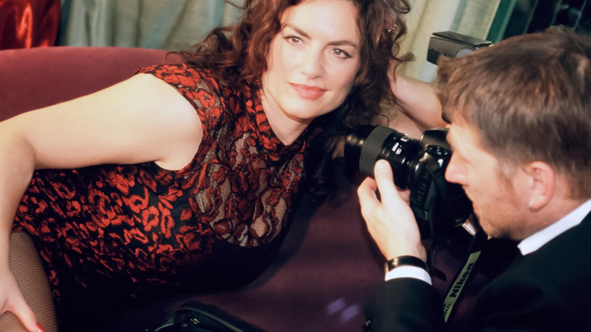 Eine Frau auf einem Sofa wird von einem Mann fotografiert.