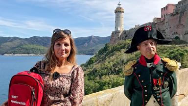 Eine Frau neben einem Stadtführer in Napoleon-Anzug.