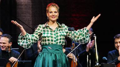 Sängerin Elīna Garanča im grüner Festkleidung und ausgebreiteten Armen