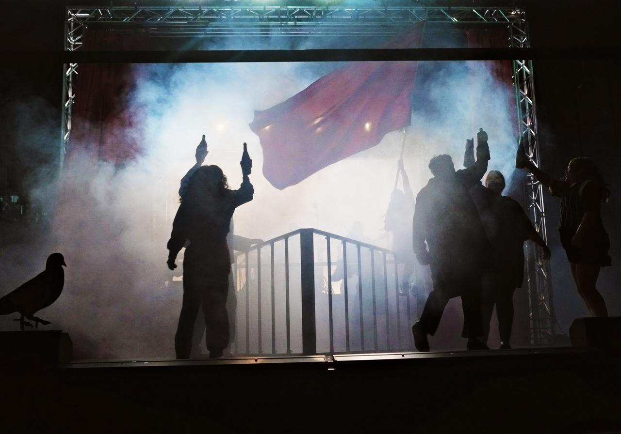 Theaterszene einer Revolution mit geschwenkter roter Fahne und viel Nebel auf der Bühne des Berliner Theaters "Hebbel am Ufer".