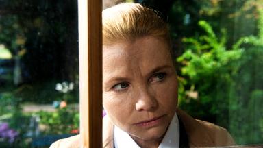 "Ella Schön - Die Inselbegabung": Ella (Annette Frier) schaut durch eine Fensterscheibe ins Innere eines Hauses.