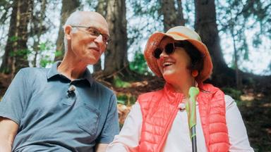 Ein älteres Paar auf einer Bank in der Natur.