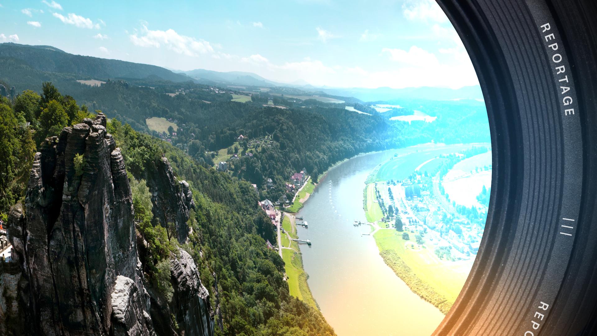 Ein sich biegender Fluss, auf der rechten Seite Flachland, auf der linken Seite Hügel und Berge. Vereinzelte Häuser am Ufer.