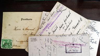 Vier alte Postkarten aufgefächert auf einer dunklen Unterlage