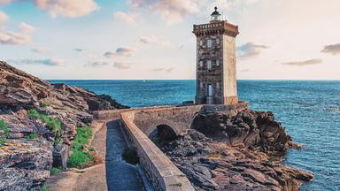 Ein Leuchtturm aus Steinen an einer Küste.