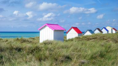 Strandhütten mit bunten Dächern an einem weißen Sandstrand.