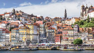 Blick auf die Altstadt von Porto, viele bunte Häuser, im Vordergrund Schiffe und Meer