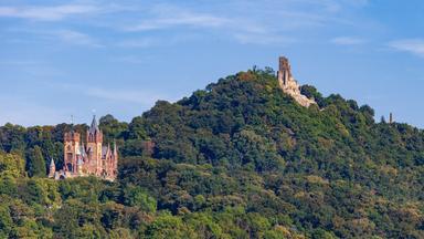 Ansicht einer Burg und einer Burgruine auf einer Hügelkette