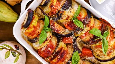 Ein Auflauf mit Aubergine und Parmesan in einer weißen Form.