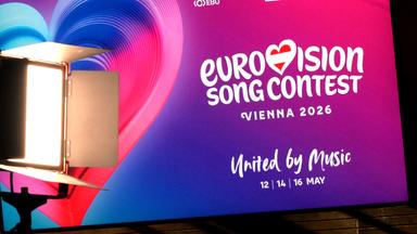 Plakat mit Werbung für den Eurovision Song Contest 2026 in Wien mit Herz in pink-lila Farben.
