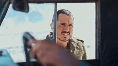 Ein junger Mann blickt durch das offene Beifahrer-Fenster eines Autos.