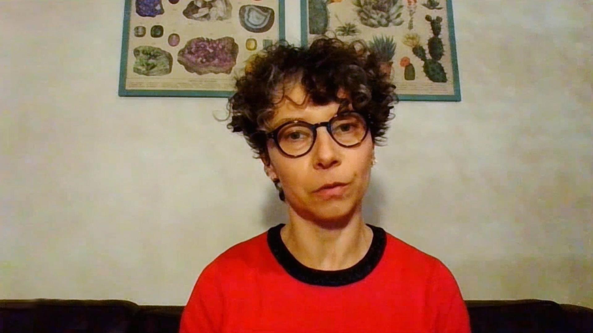 Porträtfoto einer Frau mit kurzen lockigen Haaren und großer Brille.