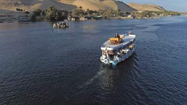 "Ewiges Ägypten - Lebensader Nil": Einzelnes Boot auf Fluss, im Hintergrund Felsen und Dünen.