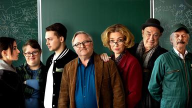 Gruppenfoto mit sieben Personen vor einer Schultafel