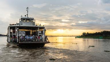 Eine Flussfähre auf dem Mekong bei untergehender Sonne.