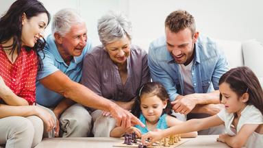Familie aus drei Generationen vor einem Schachbrett