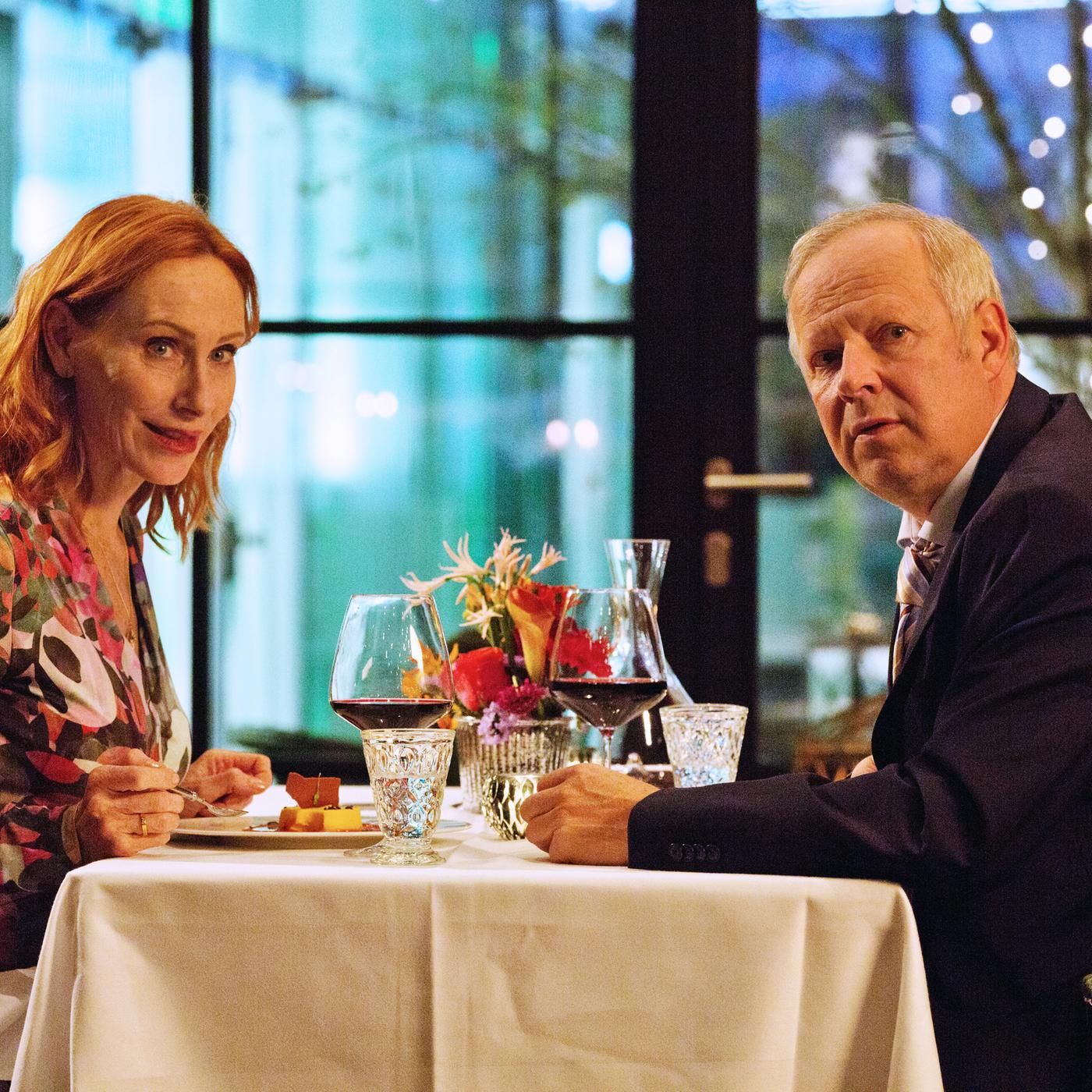 "Familie Bundschuh - Wir machen Abitur": Gundula (Andrea Sawatzki) und Gerald (Axel Milberg) sitzen in einem Restaurant am Tisch und schauen in die Kamera.