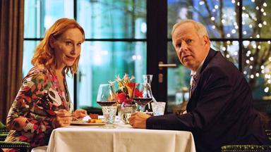 "Familie Bundschuh - Wir machen Abitur": Gundula (Andrea Sawatzki) und Gerald (Axel Milberg) sitzen in einem Restaurant am Tisch und schauen in die Kamera.