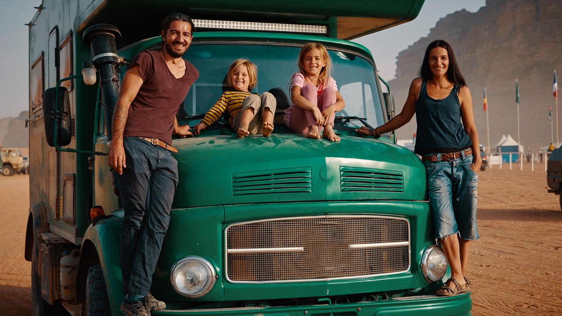 Familie Schmitt steht am grünen Lkw und lacht in die Kamera.