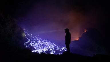 "Terra X: Fantastische Phänomene - 2. Bausteine des Lebens": Mann steht in einer dunklen Höhle vor blau-lila brennendem Schwefel.